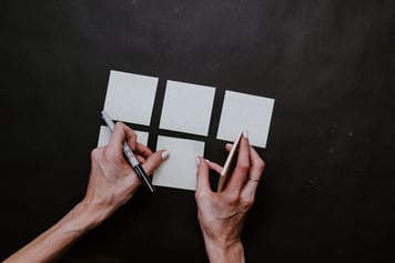 Hands organizing post-it notes into a grid system