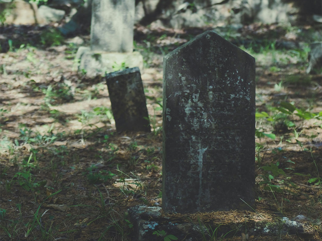 old headstone in grassy cemetery