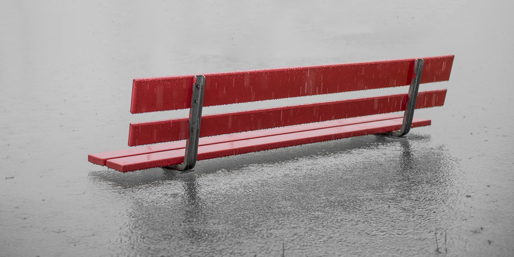 Park bench submerged in flood water and rain